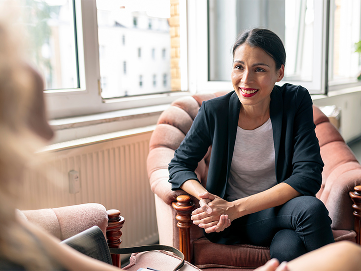 Therapist sitting across from client, leaning in and smiling  encouragingly