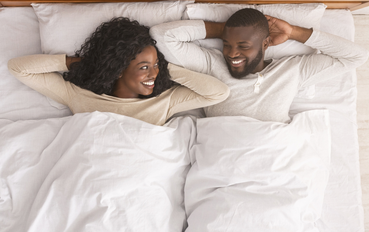 After making love. Satisfied couple of lovers relaxing in bed, lying with hands behind the head, top view