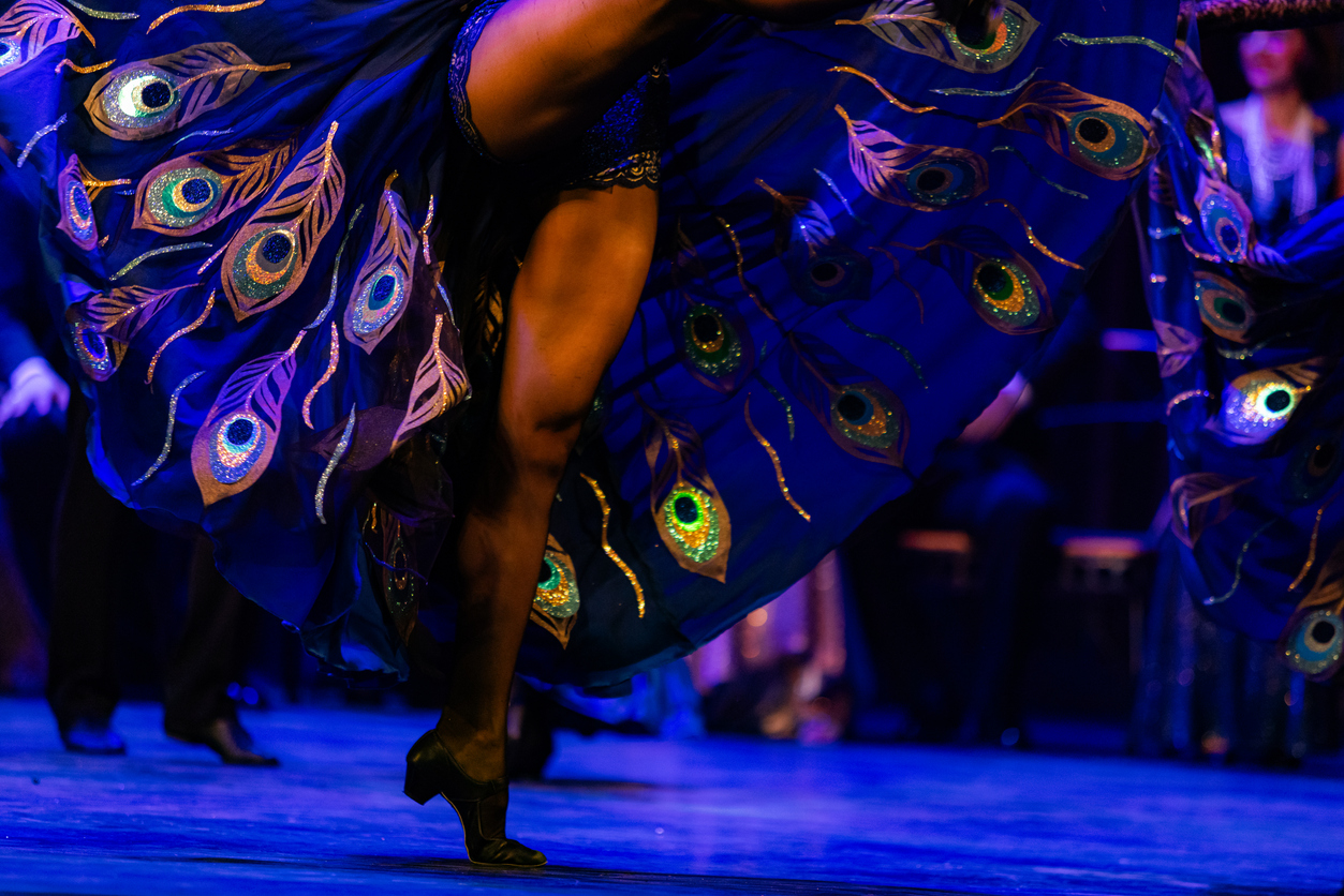 burlesque dancer's legs on stage with peacock pattern dress