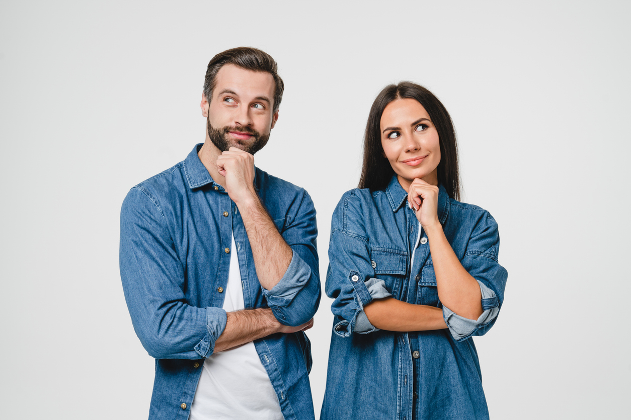 A couple standing next to each other looking slightly away from each other with bemused expressions